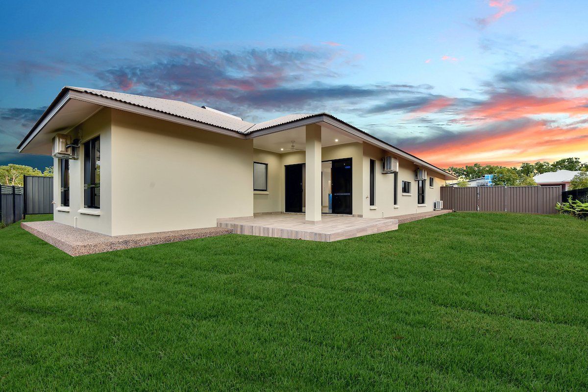A house with a large lawn in front of it and a sunset in the background.