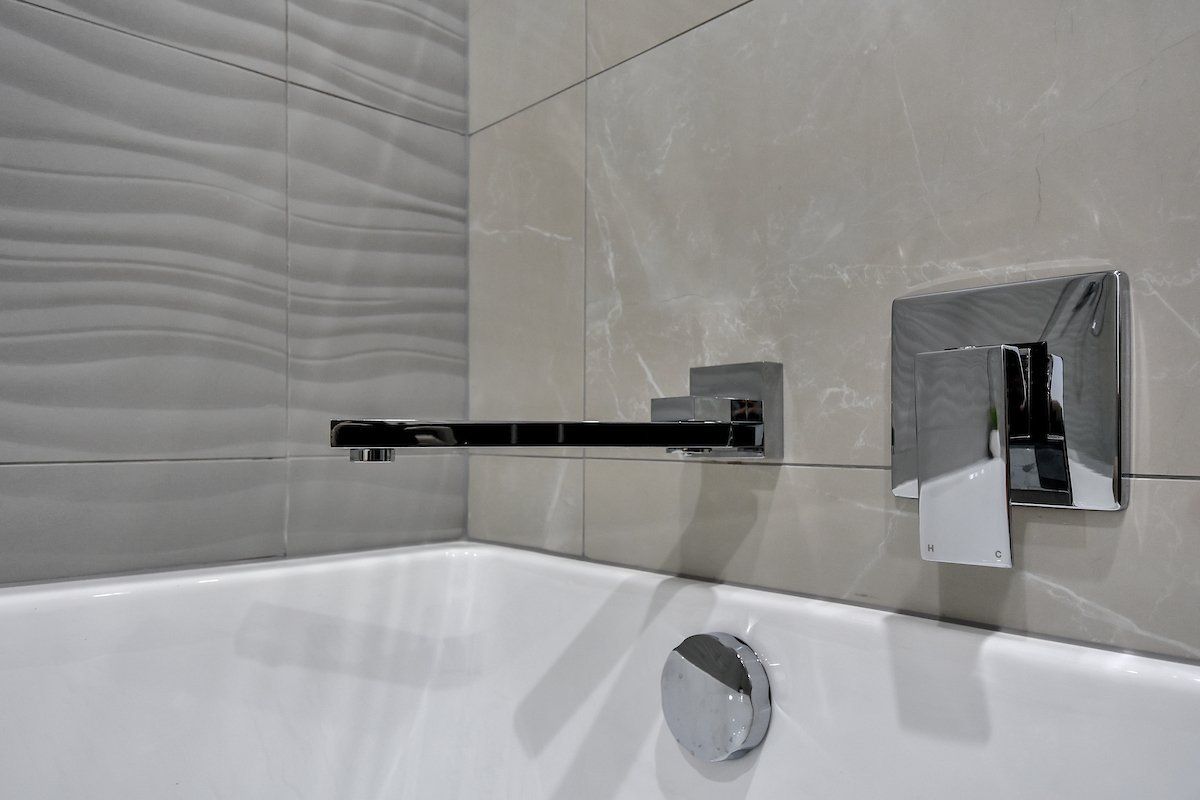 A bathroom with a bathtub and a faucet on the wall.