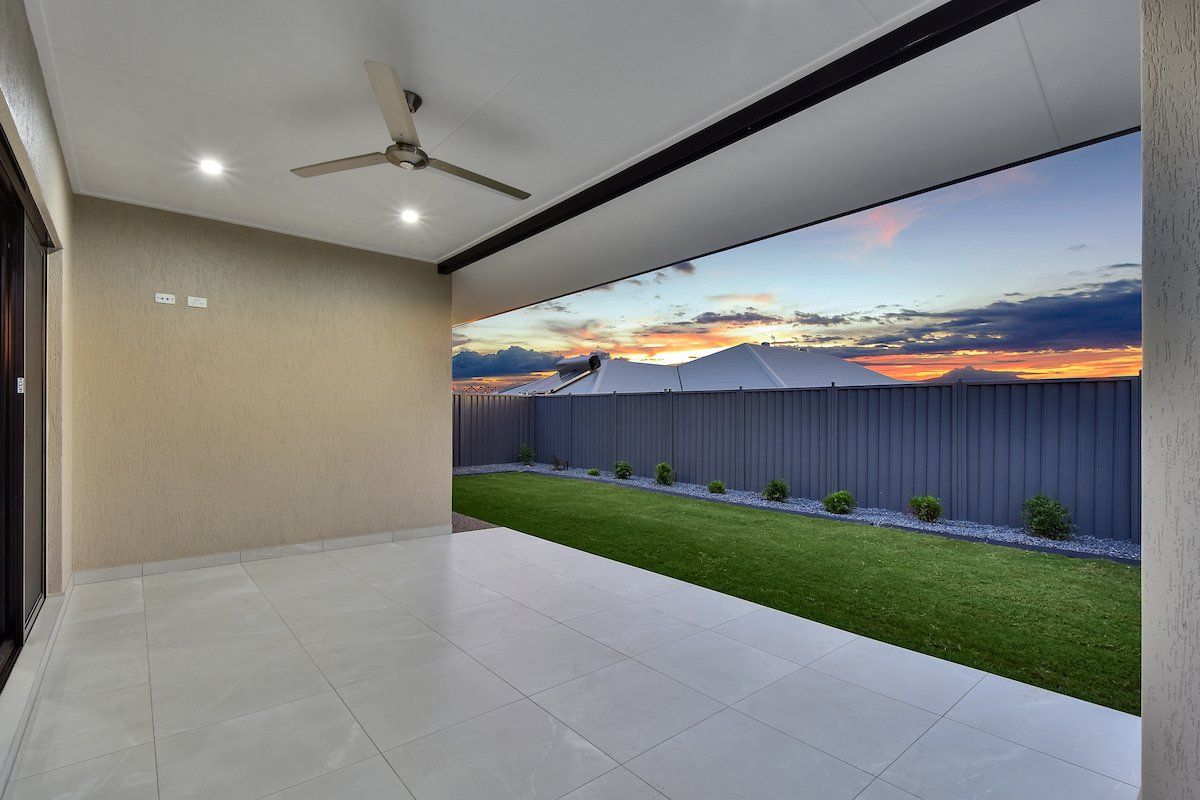An empty patio with a ceiling fan and a fence in the background.