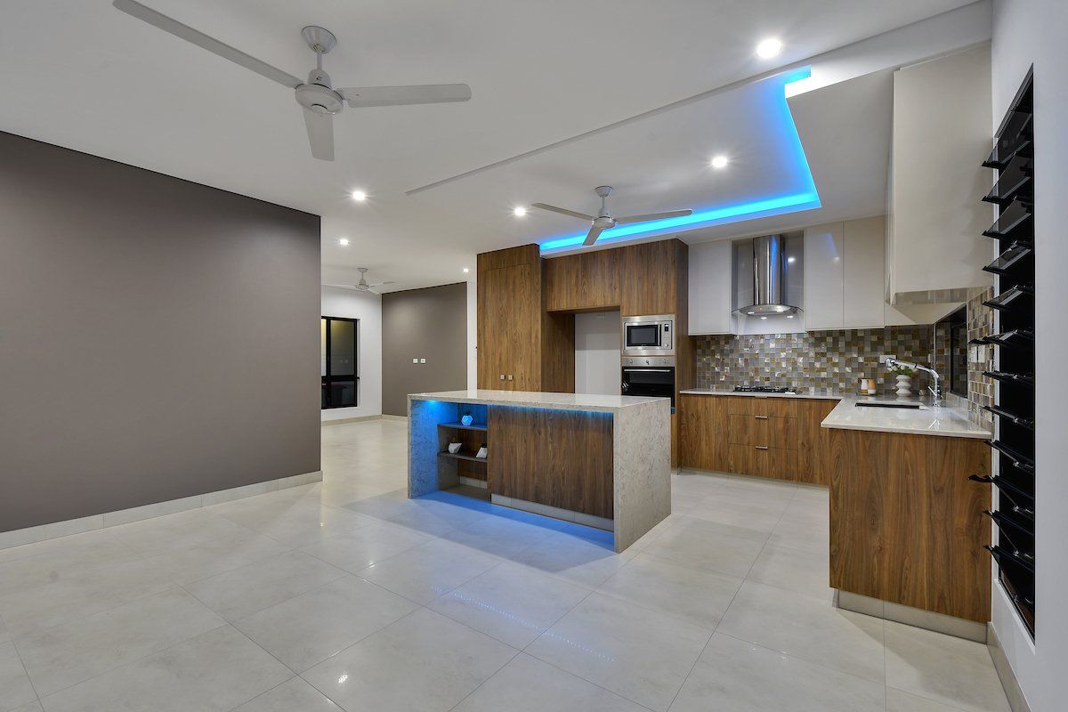 A kitchen with a blue light on the ceiling and a ceiling fan.