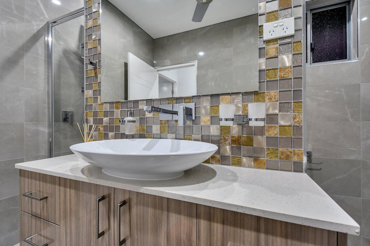 A bathroom with a sink , mirror and shower.