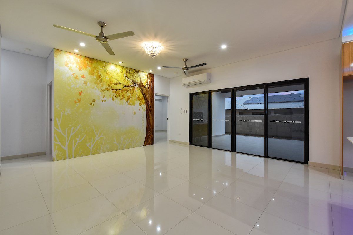 An empty living room with a ceiling fan and sliding glass doors.