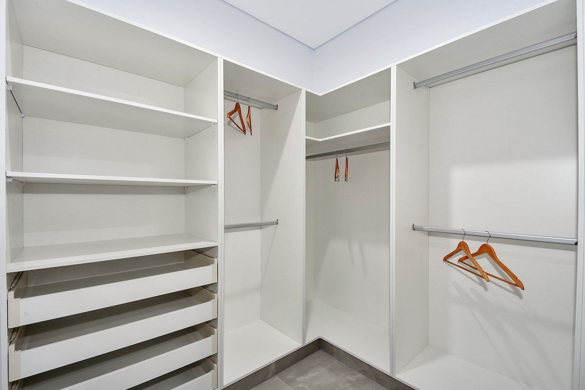 A walk in closet with a lot of shelves and hangers.