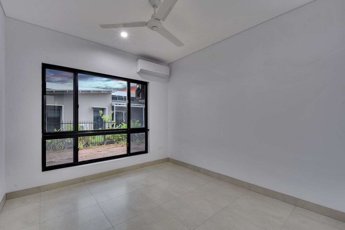 An empty room with a ceiling fan and a large window.