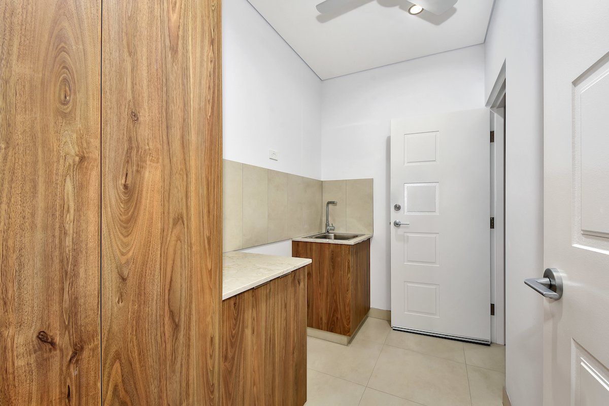 A kitchen with wooden cabinets , a sink , and a ceiling fan.