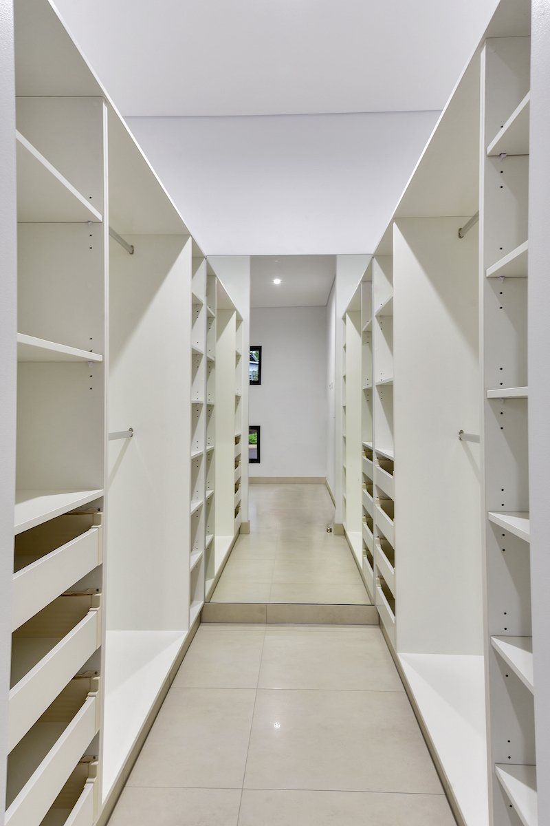 A walk in closet with lots of shelves and drawers