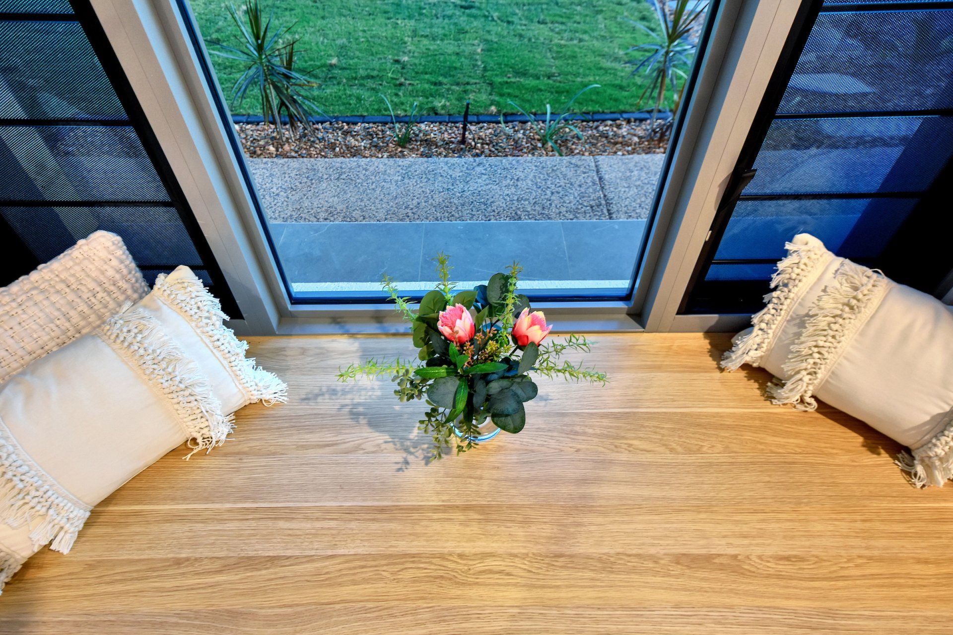 A vase of flowers is sitting on a wooden table next to a window.
