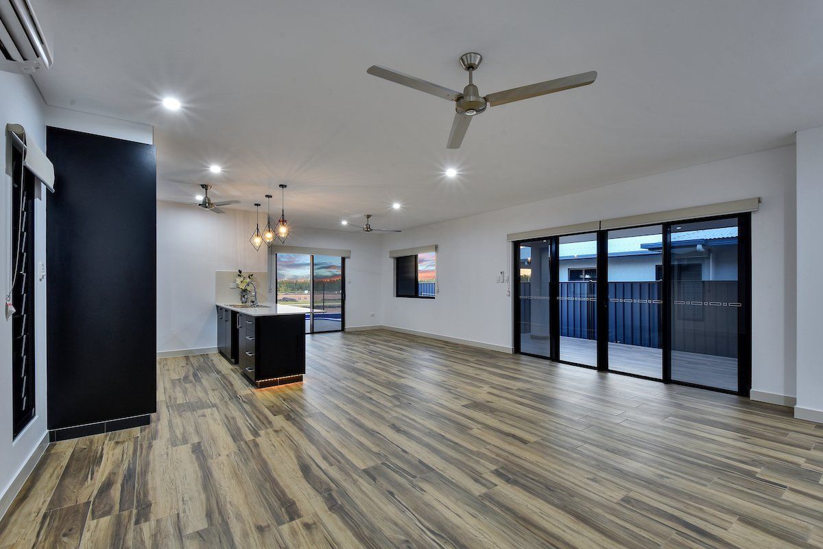 An empty living room with hardwood floors and a ceiling fan.