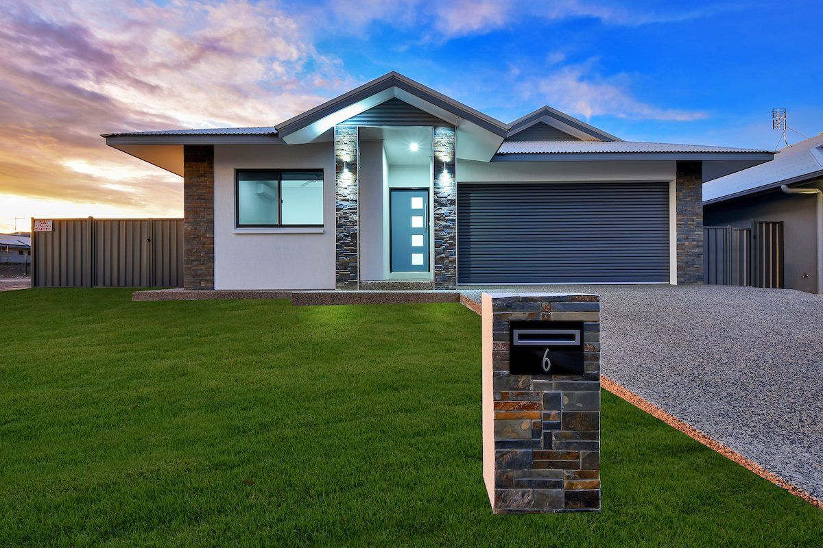 A white house with a black garage door and a mailbox in front of it.