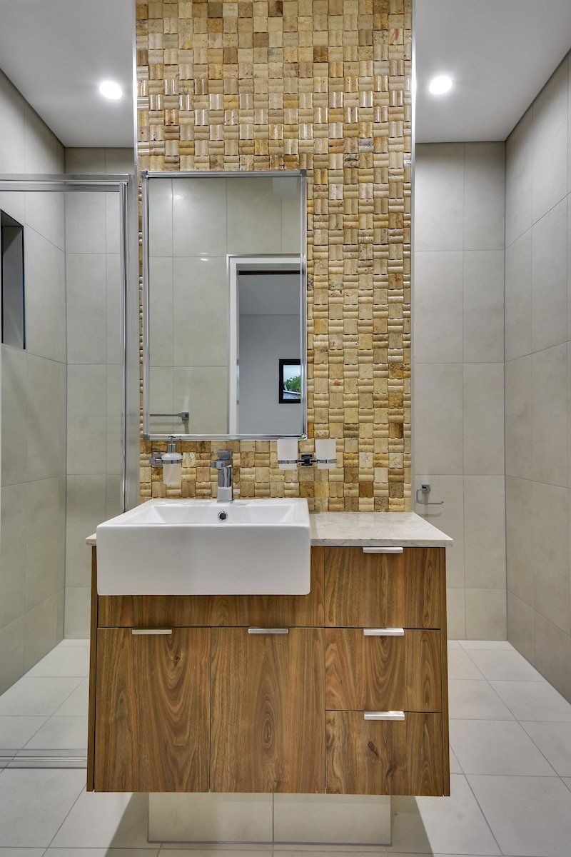 A bathroom with a sink , mirror , and wooden cabinets.