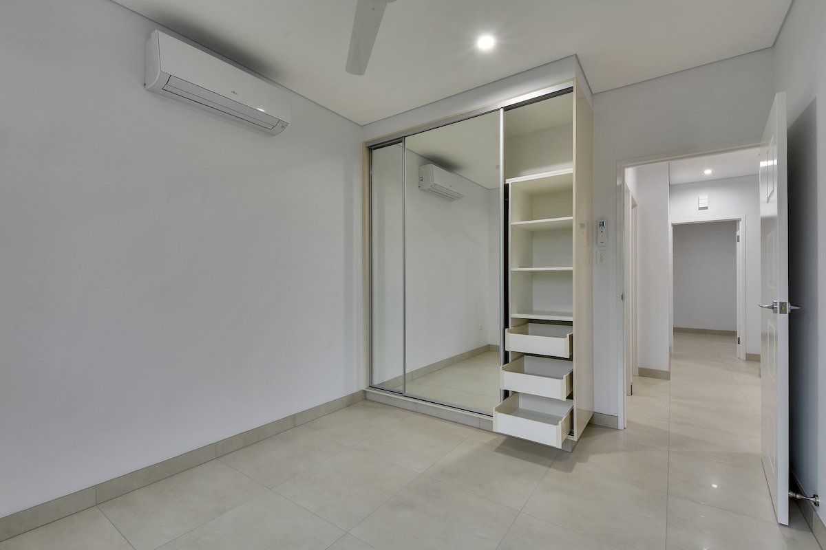An empty bedroom with a large mirrored wardrobe and drawers