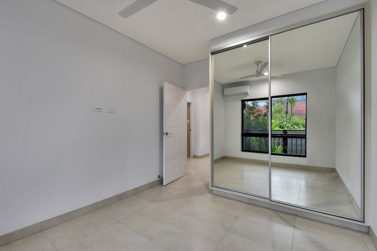 An empty bedroom with a large mirrored wardrobe and a ceiling fan.