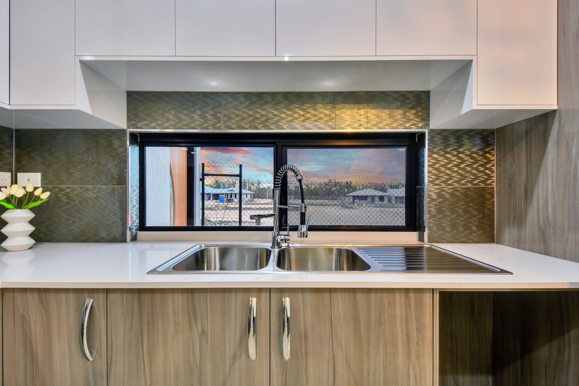 A kitchen with a sink , cabinets , and a window.