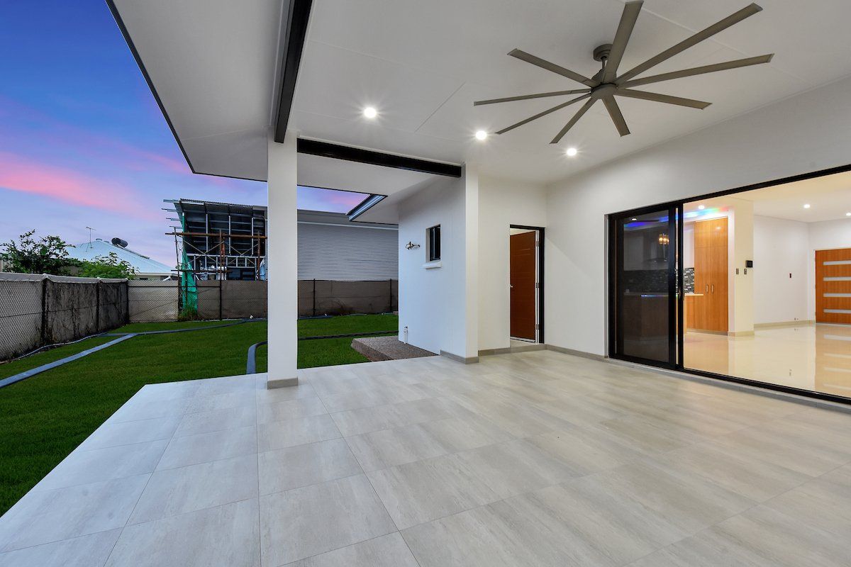 An empty patio with a ceiling fan and sliding glass doors
