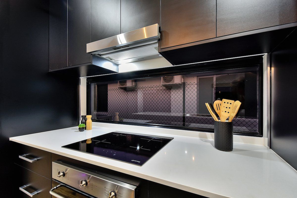 A kitchen with black cabinets and a stove top oven.