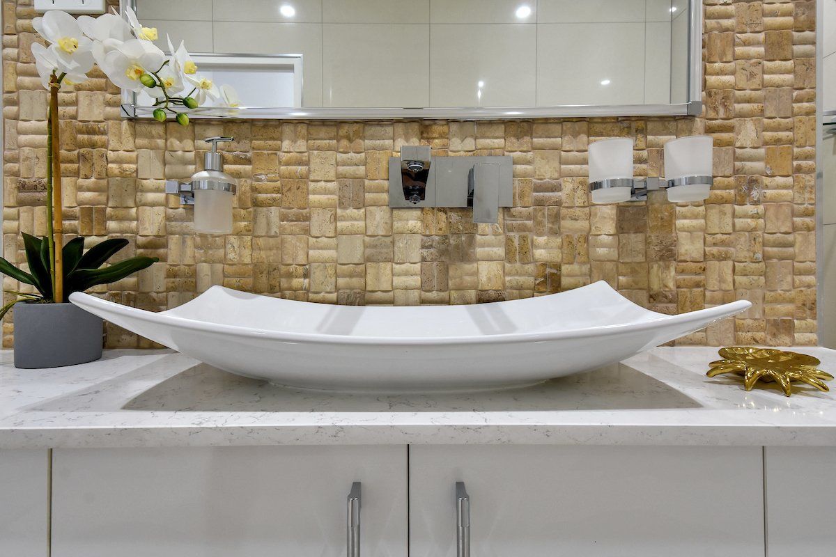 A bathroom sink with a mirror and a plant on the counter.