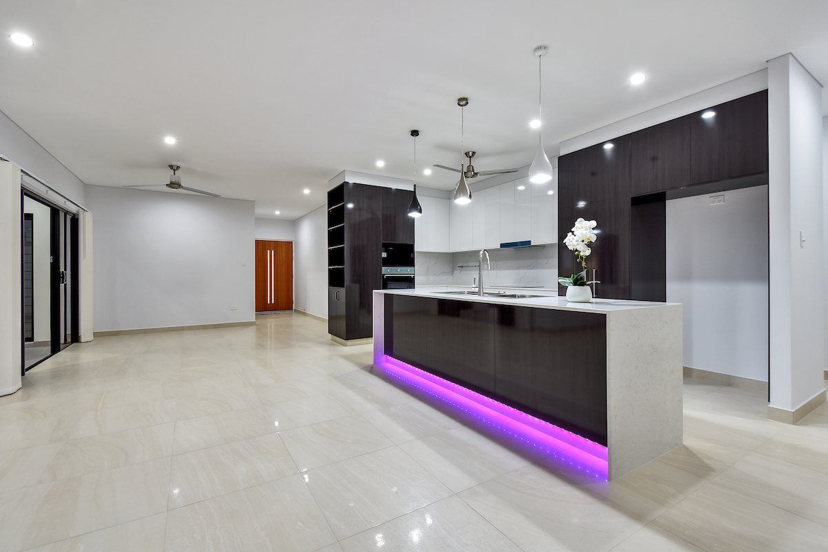 An empty kitchen with purple lights on the counter