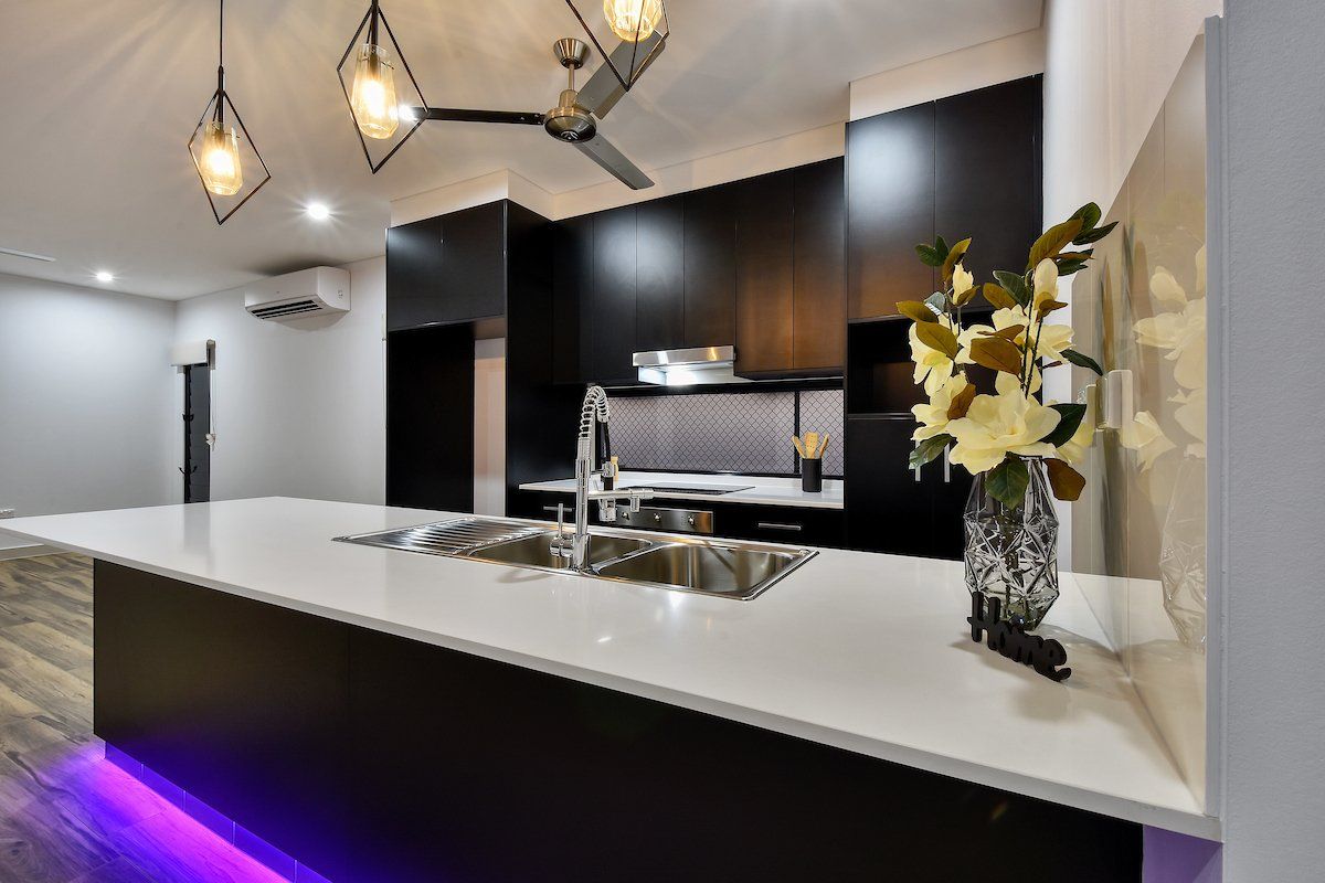 There is a vase of flowers on the counter in the kitchen.