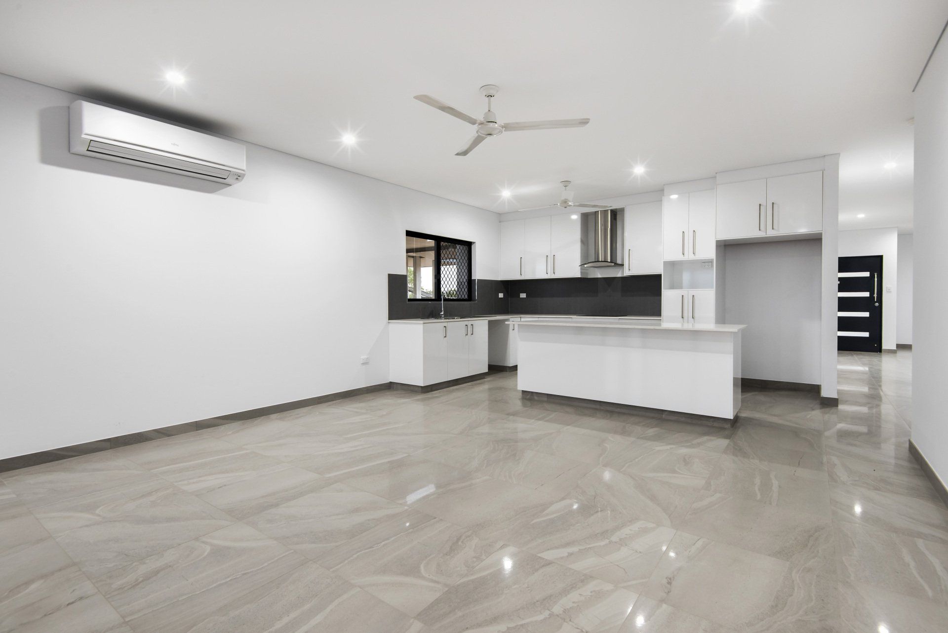 An empty kitchen with white cabinets and a ceiling fan
