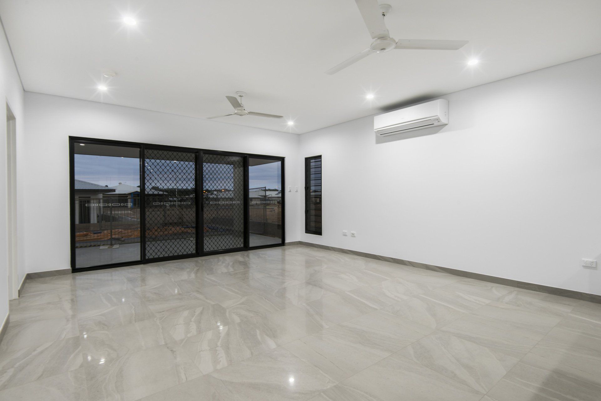 An empty living room with sliding glass doors and a ceiling fan.