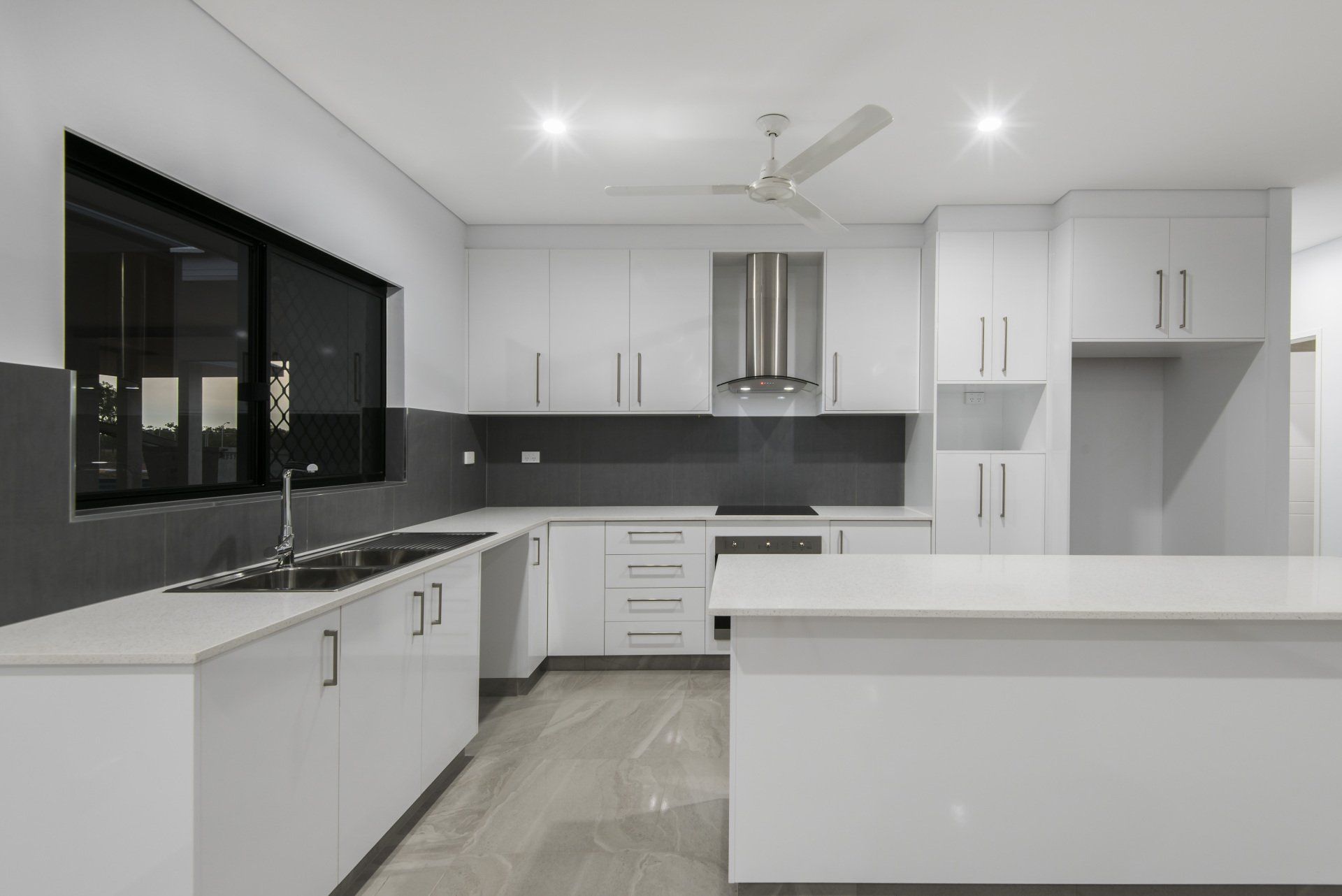 A kitchen with white cabinets and a ceiling fan