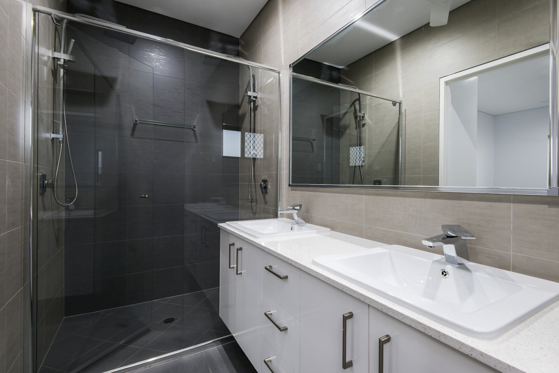 A bathroom with two sinks and a walk in shower.