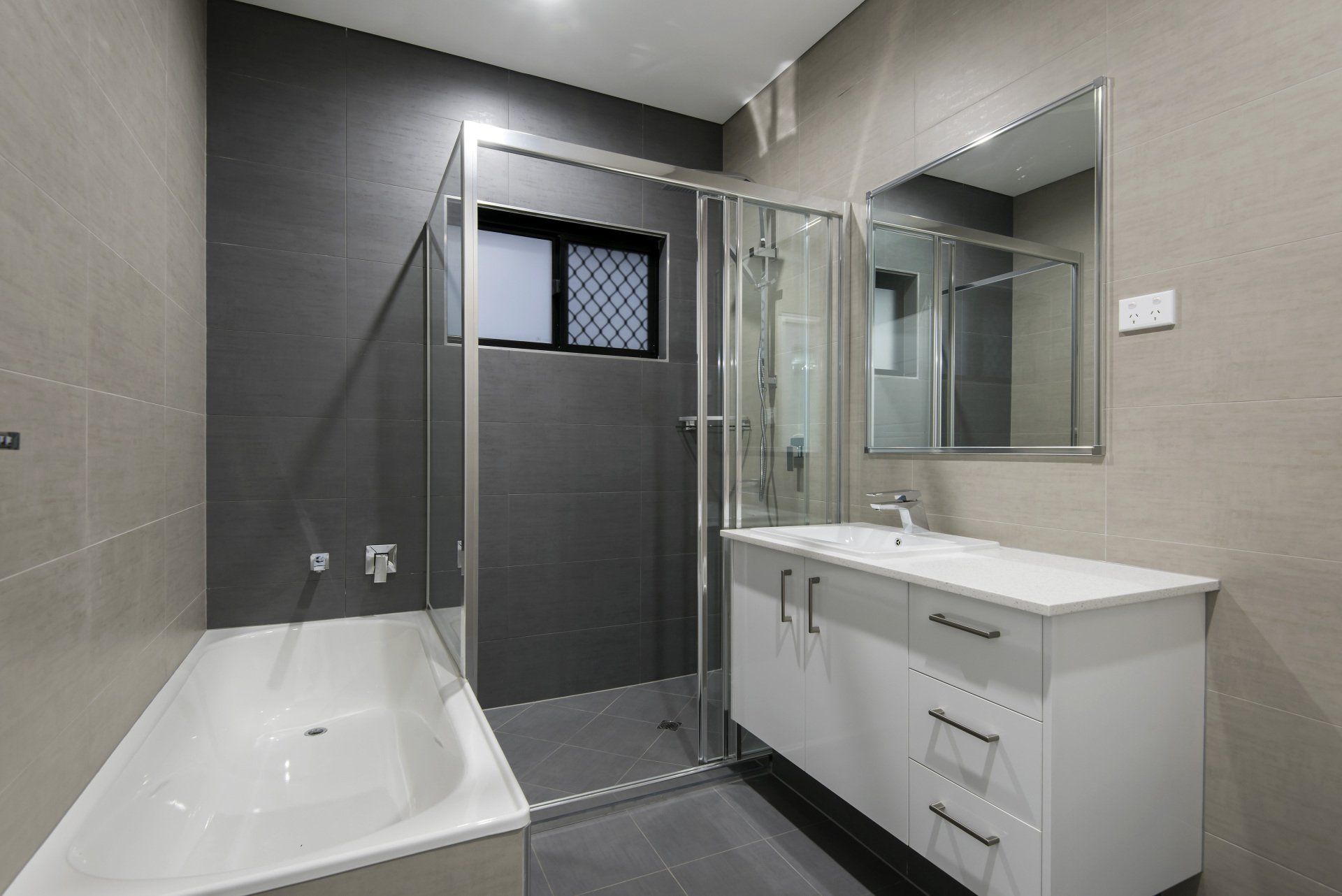 A bathroom with a tub , sink , mirror and shower.