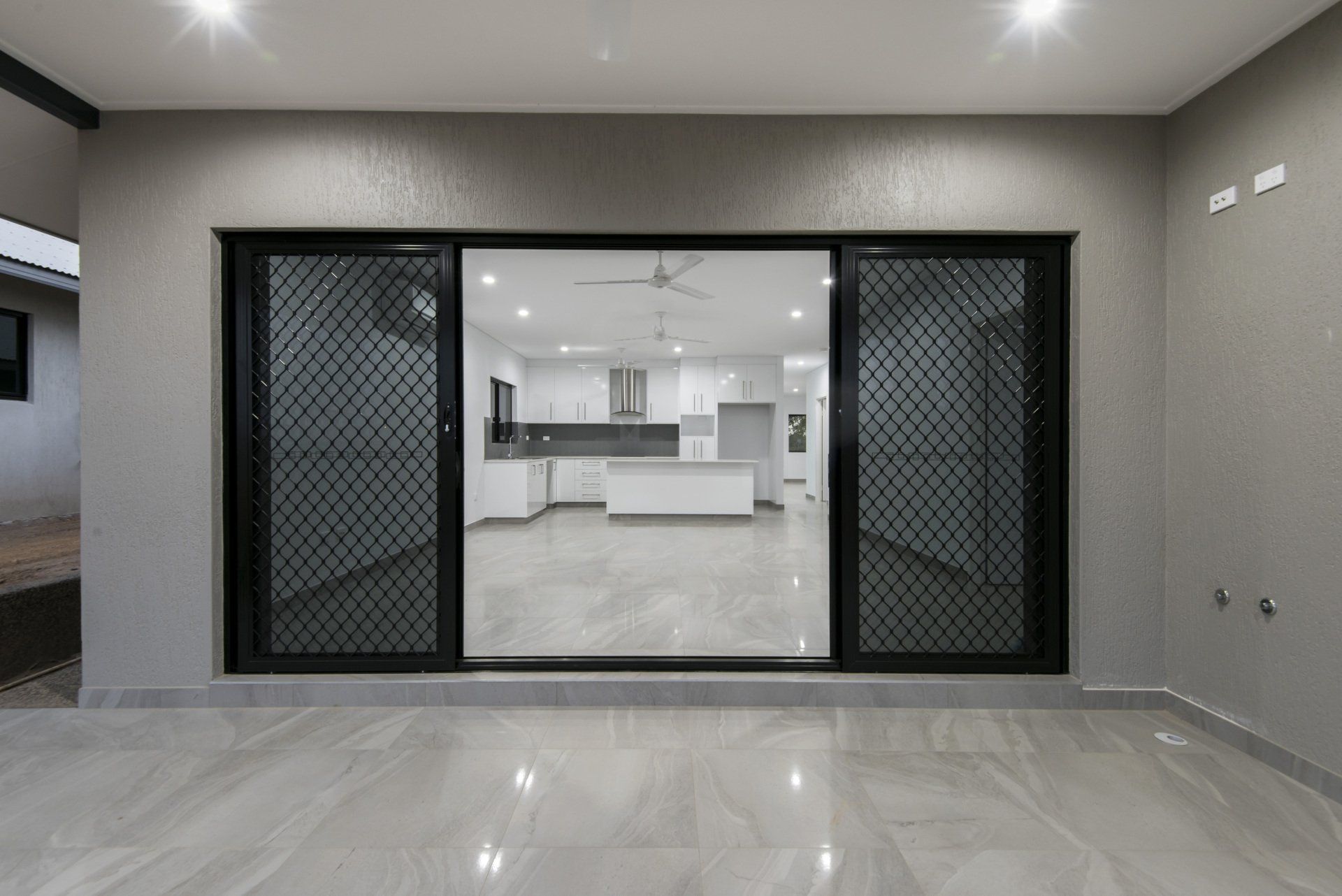 An empty room with a sliding glass door leading to a kitchen.