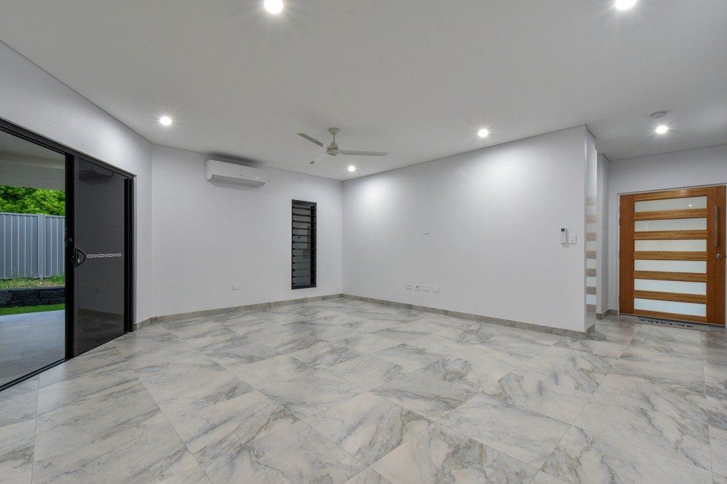 An empty living room with a ceiling fan and sliding glass doors.