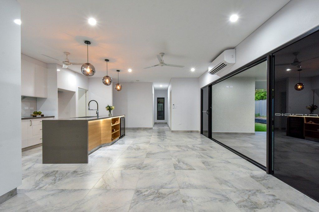 A large empty room with a kitchen and sliding glass doors.