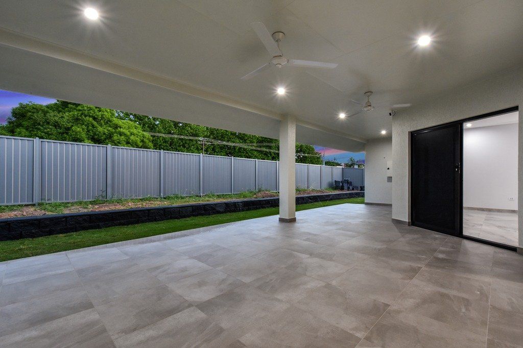 An empty patio with a ceiling fan and a fence in the background.