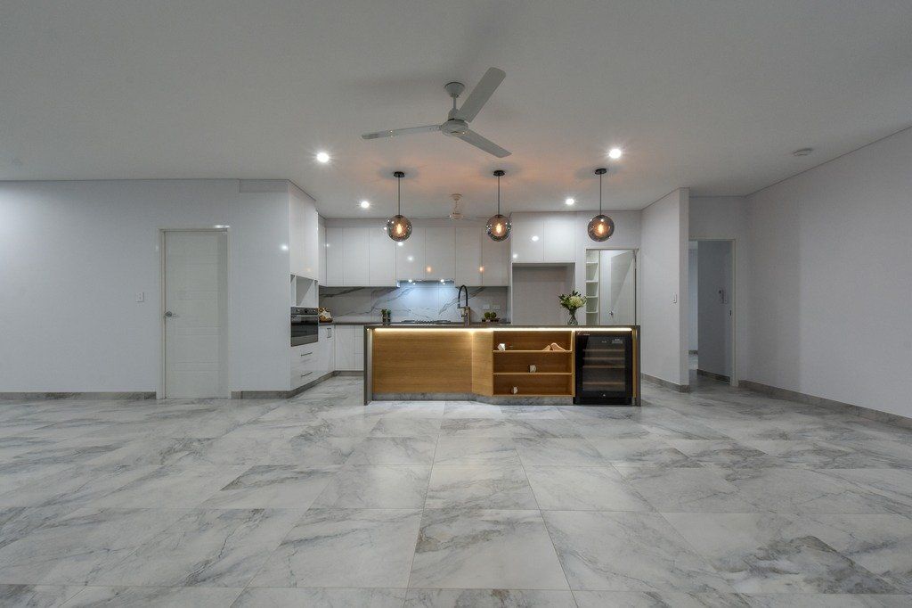 A large empty room with a kitchen and a ceiling fan.