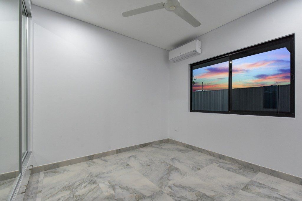 An empty room with a ceiling fan and two windows.