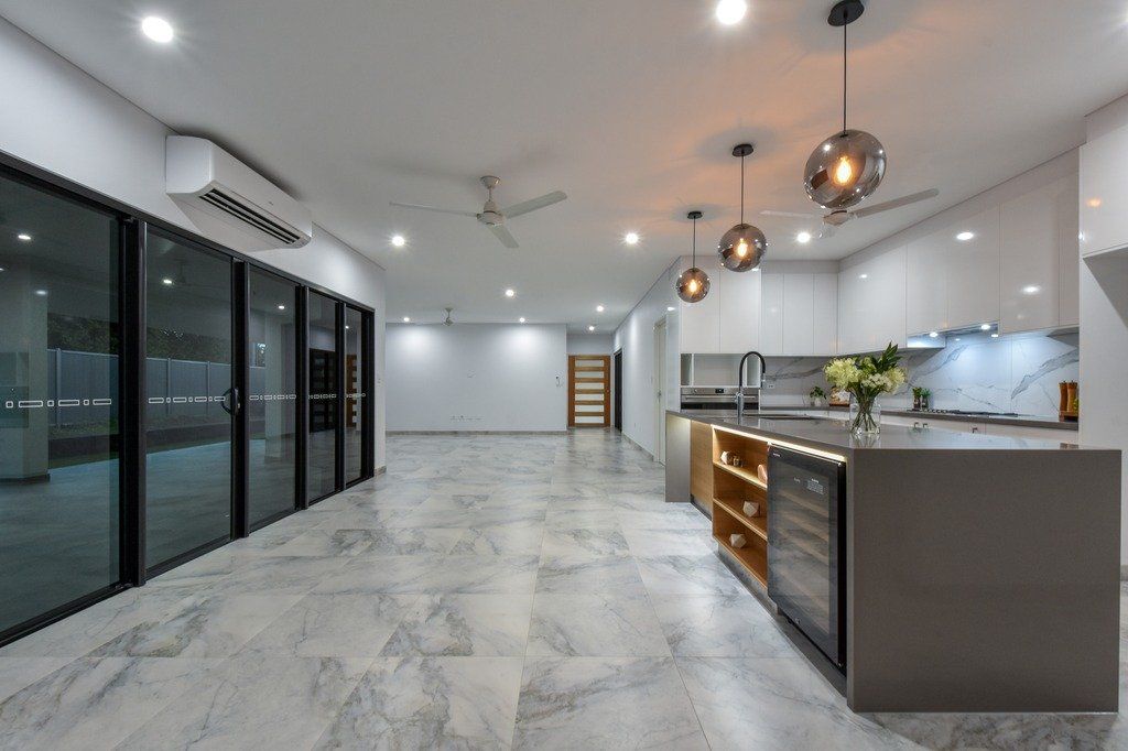 A large empty room with a kitchen and sliding glass doors.
