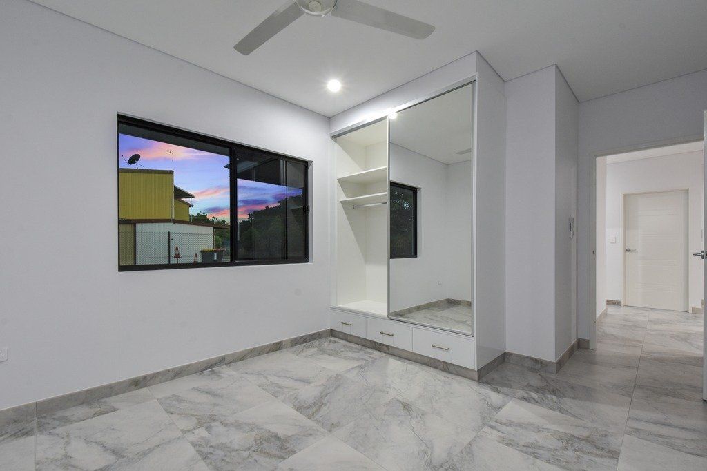 An empty room with a ceiling fan and a large mirror.