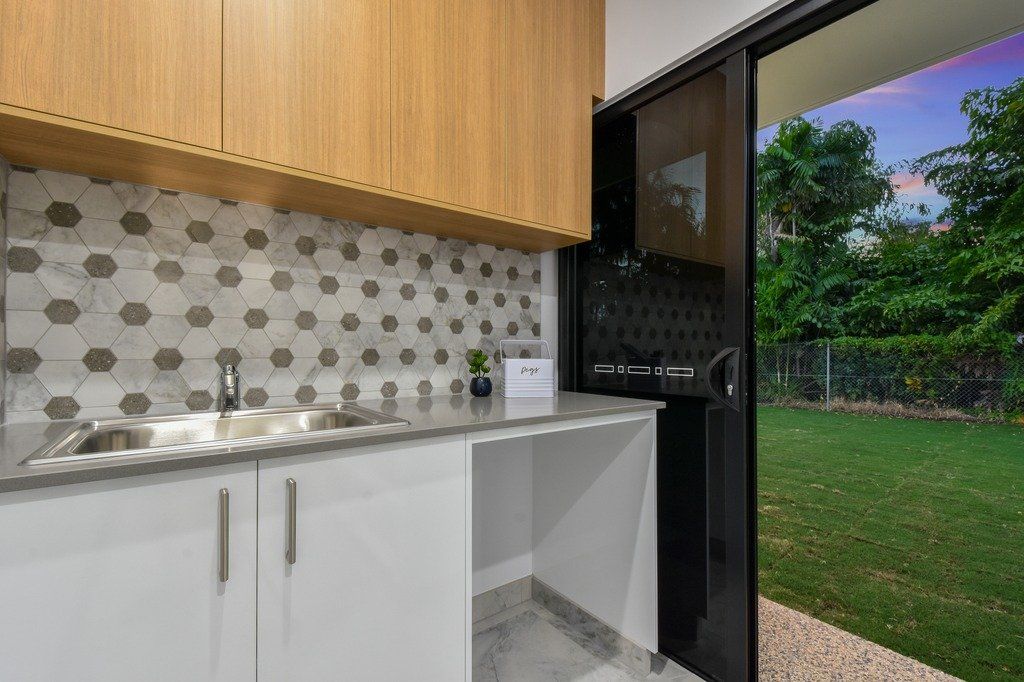 A kitchen with a sink , cabinets and a sliding glass door leading to a backyard.