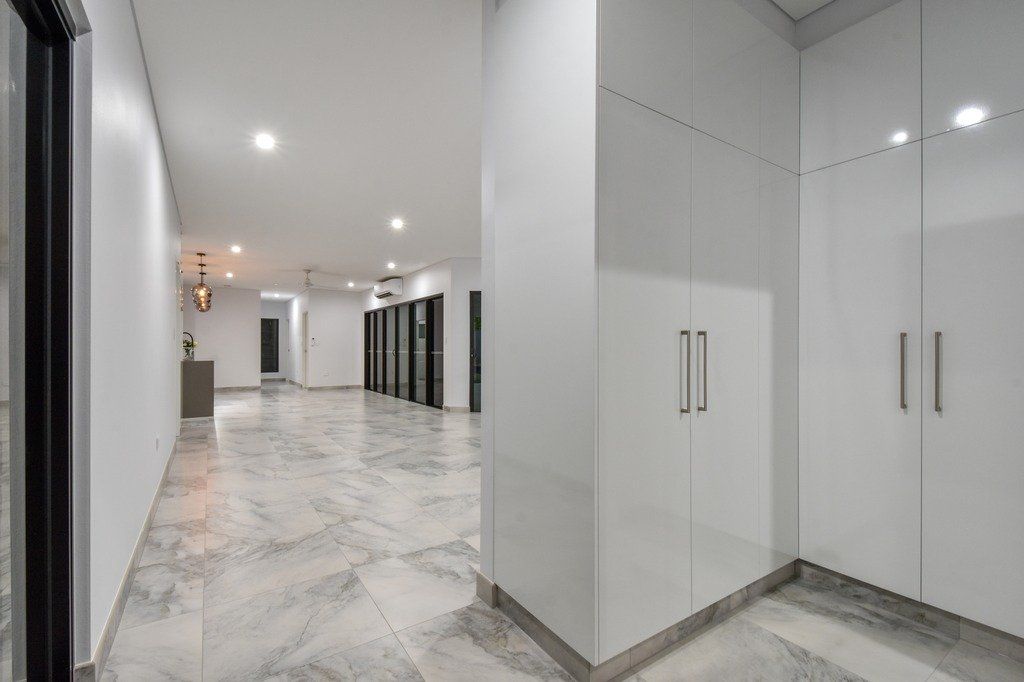 An empty hallway with white cabinets and marble floors in a house.