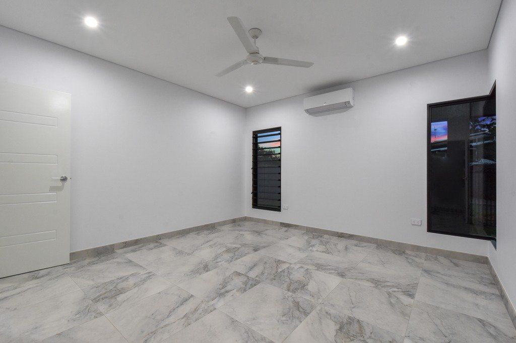 An empty room with a ceiling fan and two windows.