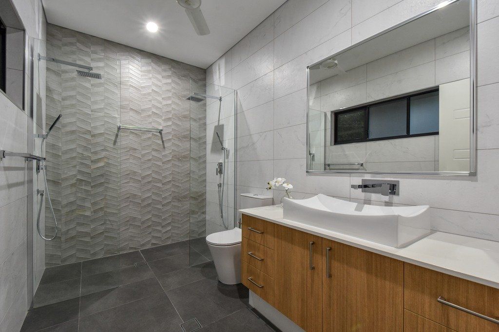 A bathroom with a sink , toilet , shower and mirror.