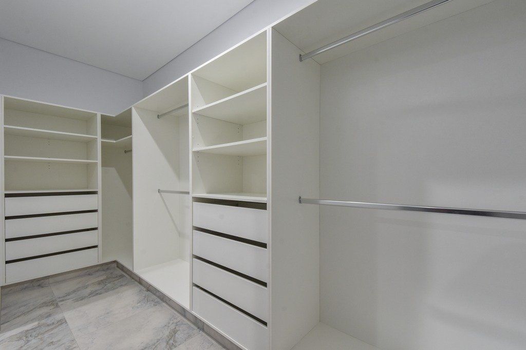 A walk in closet with lots of shelves and drawers.