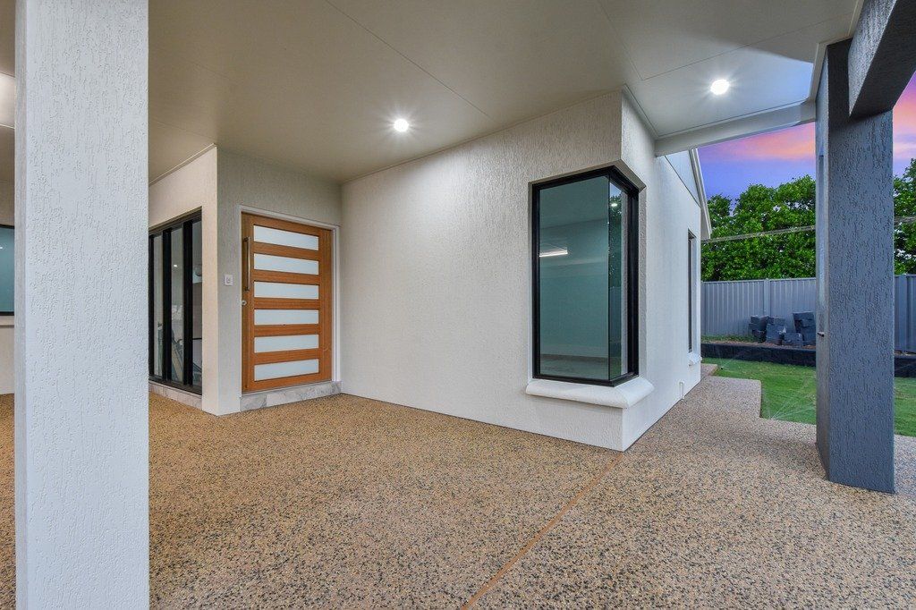 A white house with a gravel driveway in front of it.