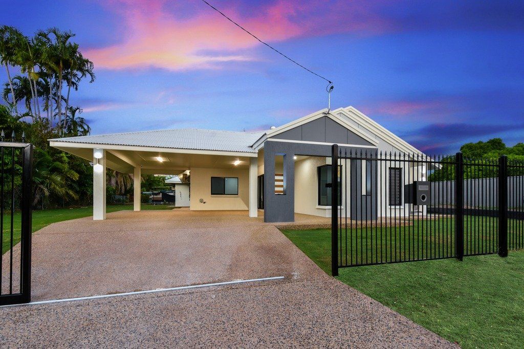 A house with a driveway and a fence in front of it.