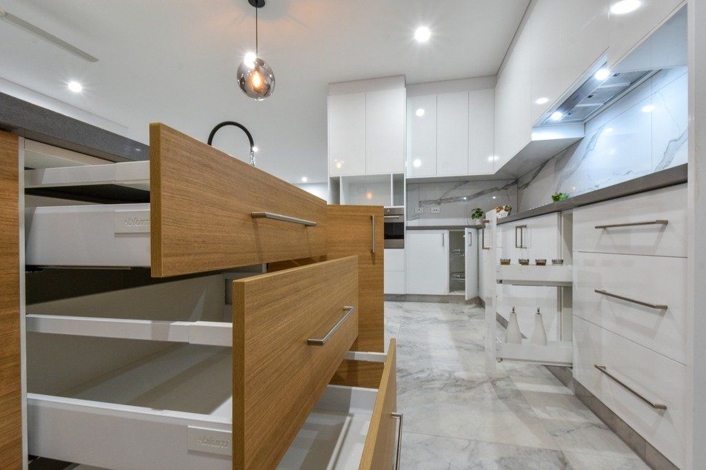 A kitchen with white cabinets and wooden drawers.