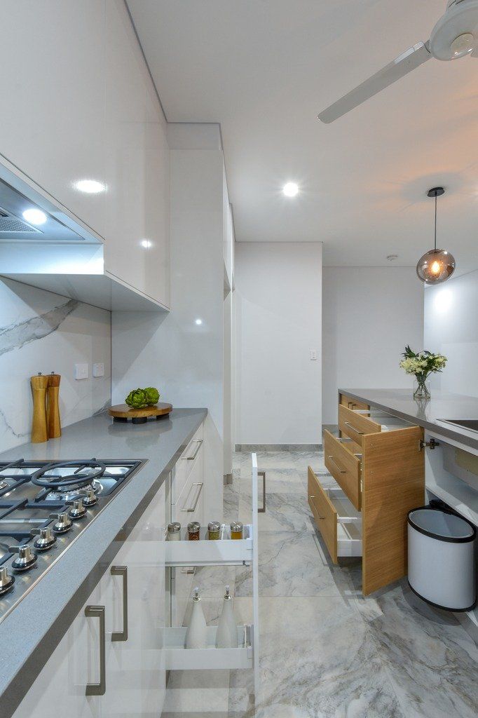 A kitchen with white cabinets and drawers and a stove top oven.