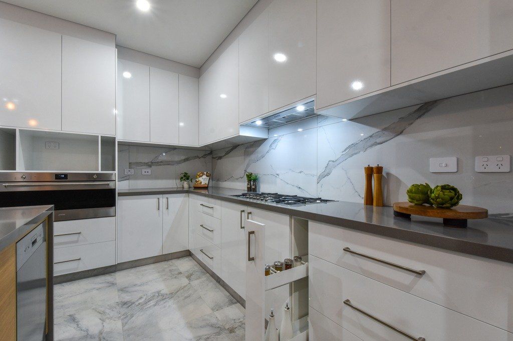 A kitchen with white cabinets , granite counter tops , and stainless steel appliances.