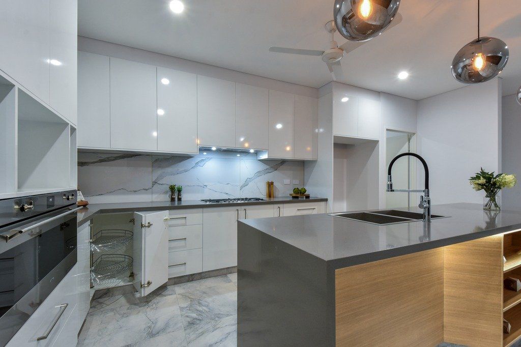 A kitchen with white cabinets , a sink , and a stove.