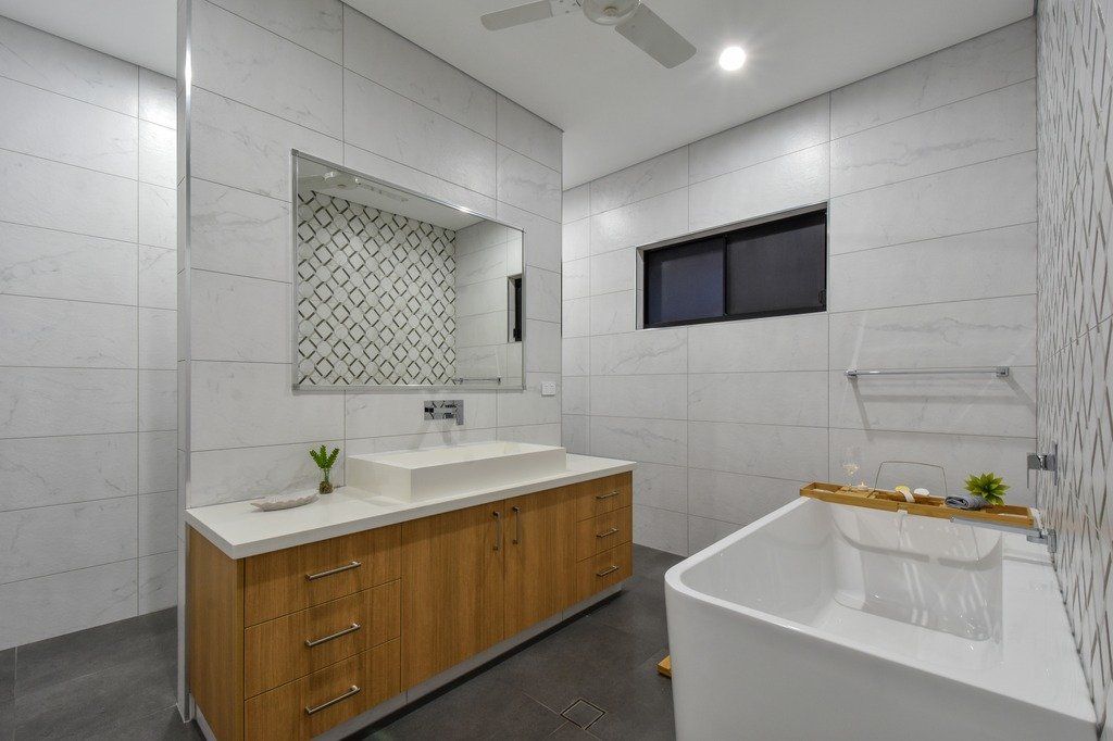A bathroom with a tub , sink , mirror and ceiling fan.