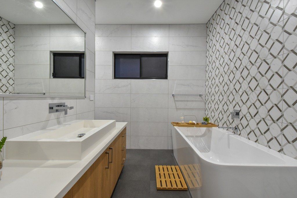 A bathroom with a bathtub , sink and mirror.