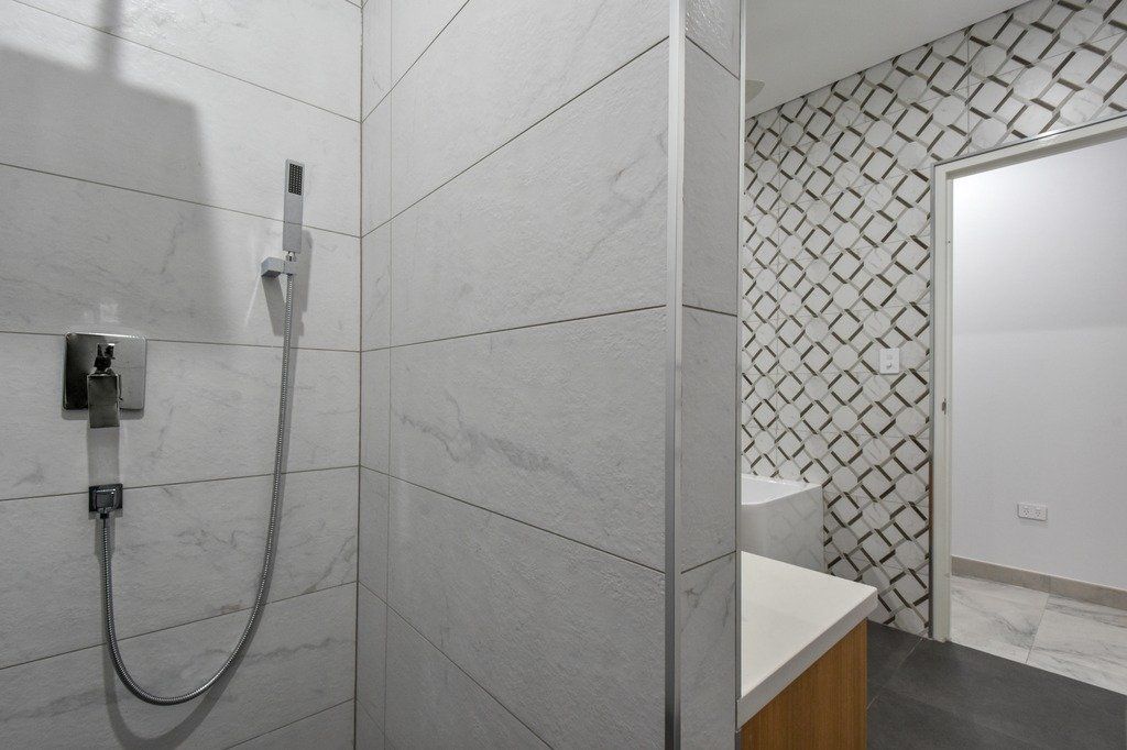 A bathroom with a shower and a sink with a geometric pattern on the wall.