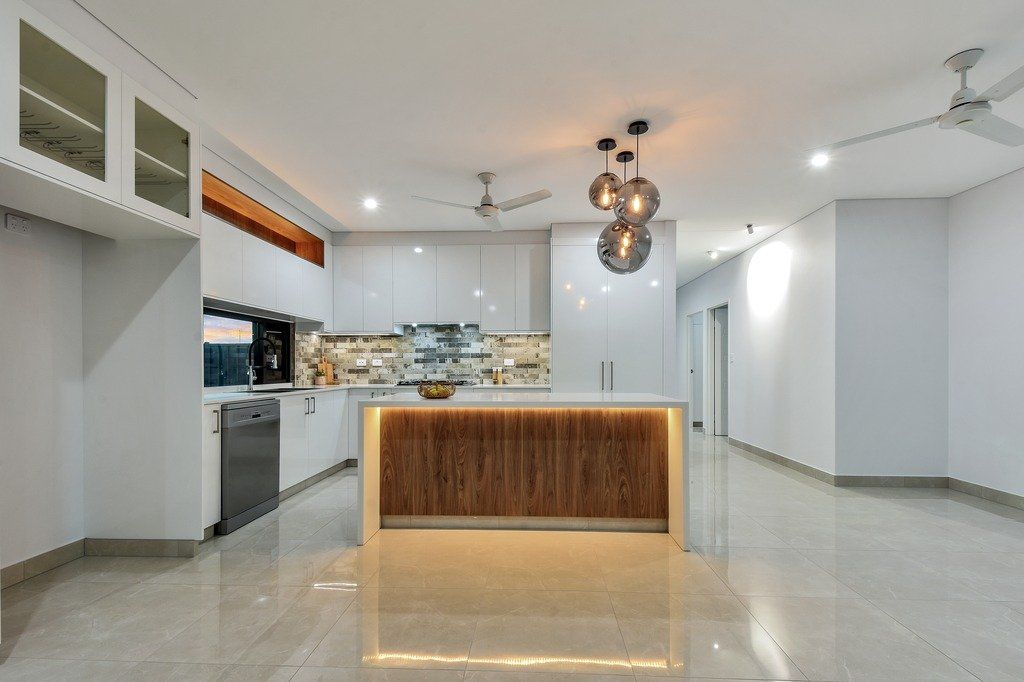 An empty kitchen with a large island and a ceiling fan.